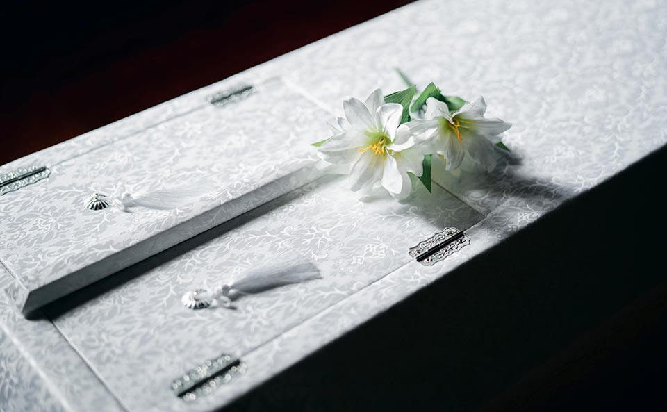 白い棺の上に花が置かれています